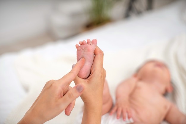 Close-up de massagem nos pés das crianças na cama. Foco seletivo na perna da criança.