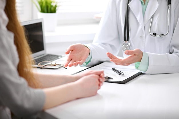 Close-up de médico e paciente sentado na mesa perto da janela no hospital