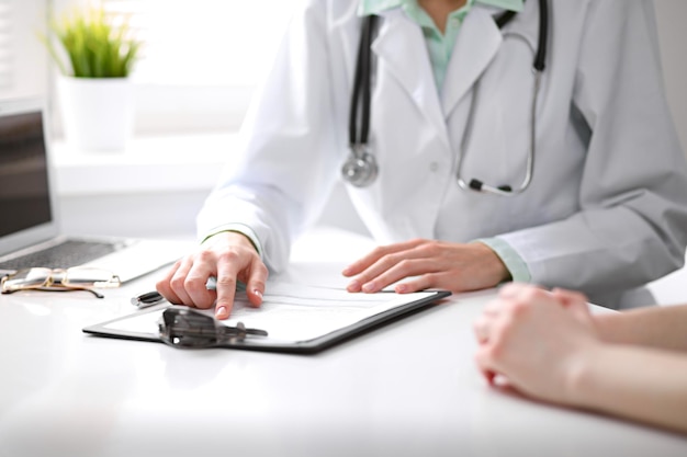 Close-up de médico e paciente sentado na mesa perto da janela no hospital