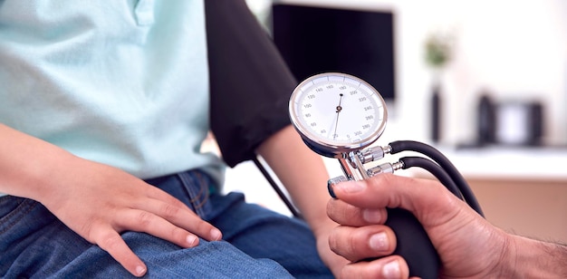 Close-up de médico masculino ou gp examinando menino tomando pressão arterial com esfigmomanômetro