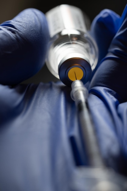 Close-up de médicos com a seringa na mão com o frasco
