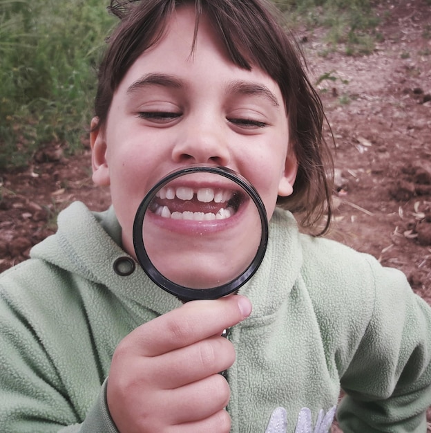 Foto close-up de menina segurando uma lupa no campo