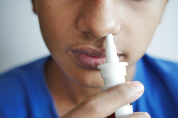 Close-up de menino doente usando spray de remédio nasal