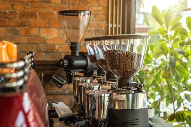 Close-up de moedor elétrico preto profissional e máquina de café expresso está em uma mesa de madeira em uma cafeteria em um café