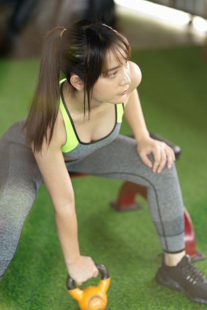 Close-up de mulher bonita fitness tenta levantar um kettlebell no chão, conceito de equipamento de esporte.