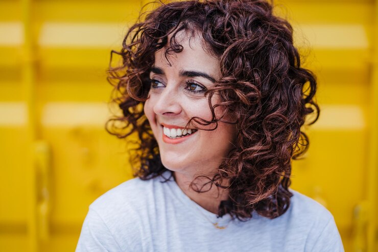 Foto close-up de mulher caucasiana feliz com cabelo encaracolado sobre fundo amarelo tempo de verão