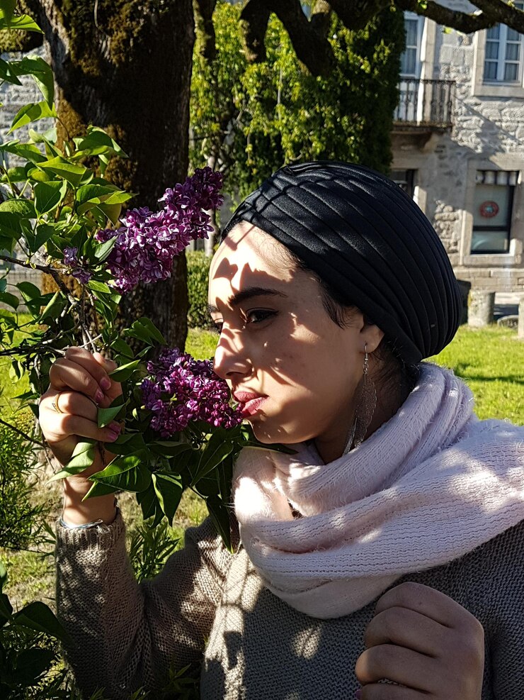 Foto close-up de mulher cheirando plantas com flores roxas
