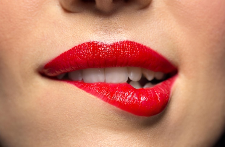 Foto close-up de mulher com batom vermelho mordendo lábio