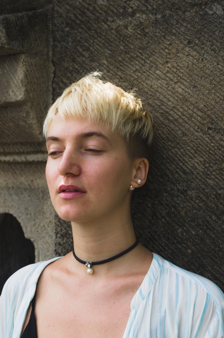 Foto close-up de mulher com cabelo curto de pé junto à parede