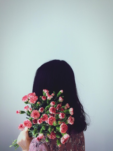Close-up de mulher com flores cor-de-rosa contra fundo azul