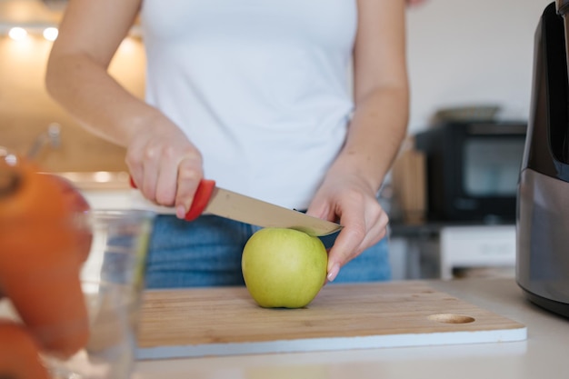 Foto close-up de mulher cortando maçã na cozinha, mulher preparando legumes e frutas para suco caseiro