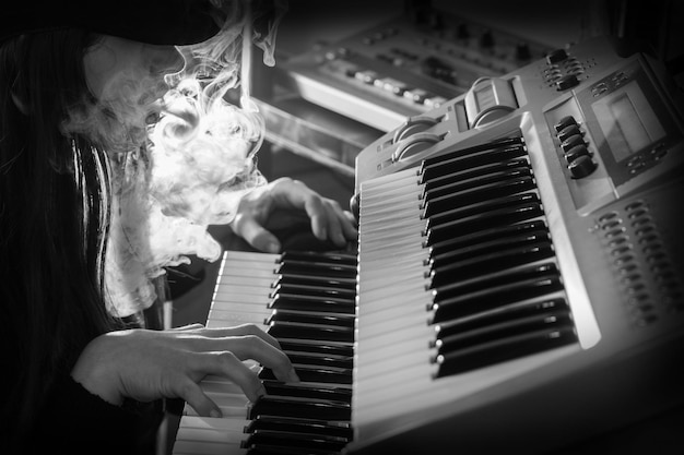 Foto close-up de mulher exalando fumaça enquanto toca piano