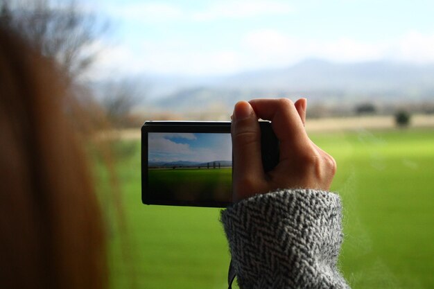 Foto close-up de mulher fotografando usando telefone celular no campo