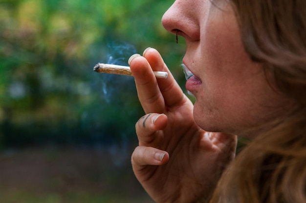 Foto close-up de mulher fumando maconha ao ar livre