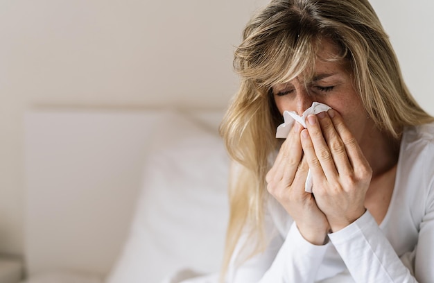 Close-up de mulher insalubre na cama golpe no guardanapo sofre de gripe ou resfriado Indisposto doente luta contra o fungo do milênio com sintomas de vírus tem coriza Corona covid19 imagem conceitual