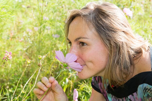 Close-up de mulher jovem e bonita contra rosa flores verdes do parque de verão