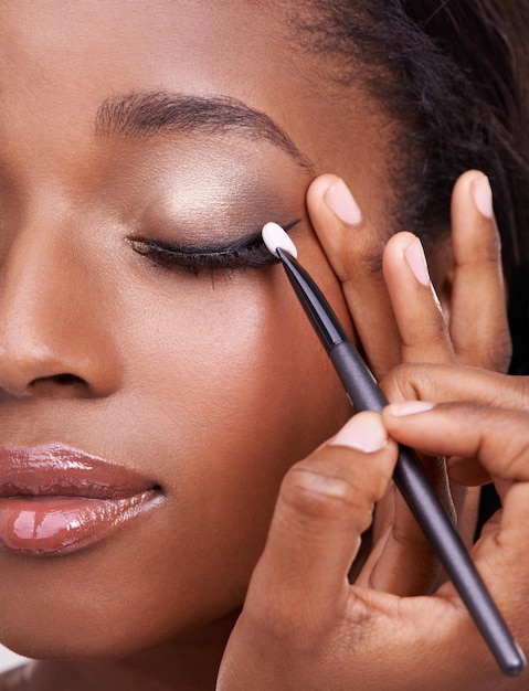 Foto close-up de mulher negra escova e sombra de olhos com maquiagem beleza e pestanas com delineador de olhos pele brilho mãos e aplicação de produtos cosméticos com ferramentas para cosmetologia brilho ou brilho com brilho