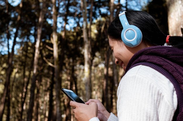 Foto close-up de mulher ouvindo música enquanto usa telefone celular no parque