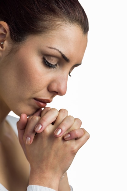 Foto close-up de mulher rezando com mãos juntas e olhos fechados