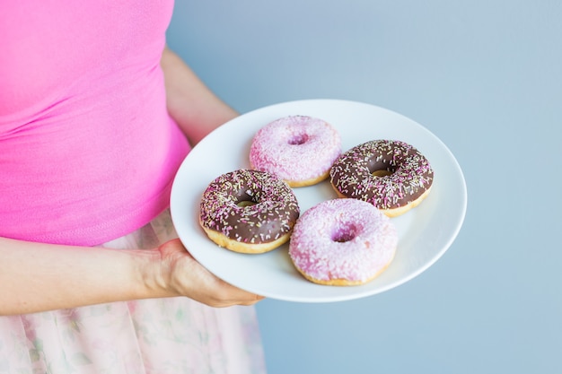 Close-up de mulher segurando o prato com deliciosos donuts doces.