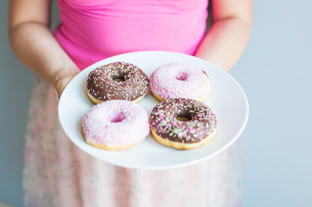 Close-up de mulher segurando o prato com deliciosos donuts doces.