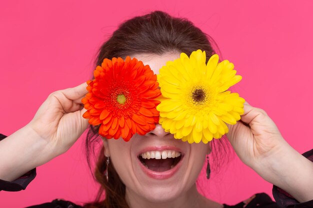 Foto close-up de mulher segurando uma flor amarela contra fundo vermelho