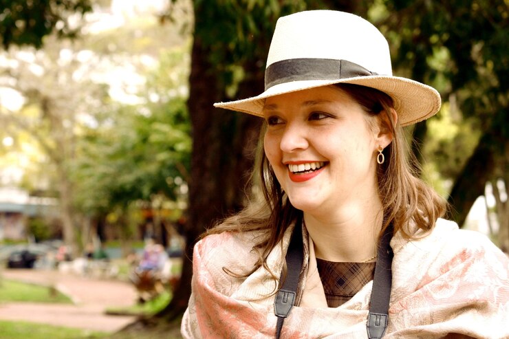 Foto close-up de mulher sorridente vestindo chapéu olhando para o quintal