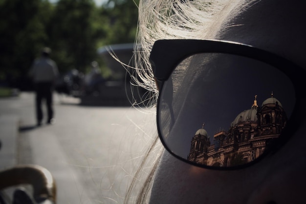 Foto close-up de mulher usando óculos de sol com reflexo do edifício