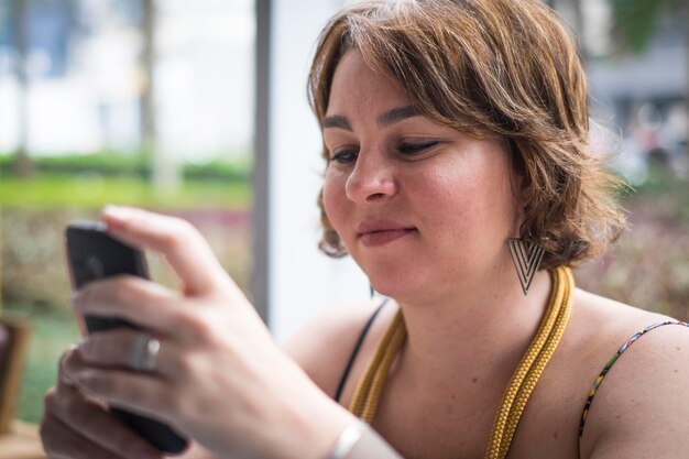 Close-up de mulher usando smartphone enquanto está sentada ao ar livre