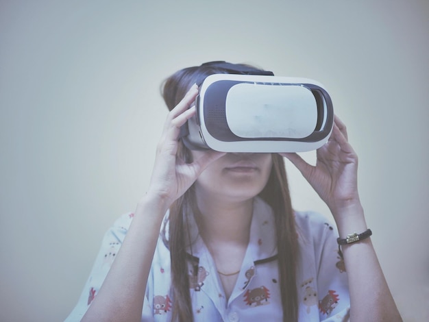 Close-up de mulher usando um simulador de realidade virtual contra um fundo cinzento