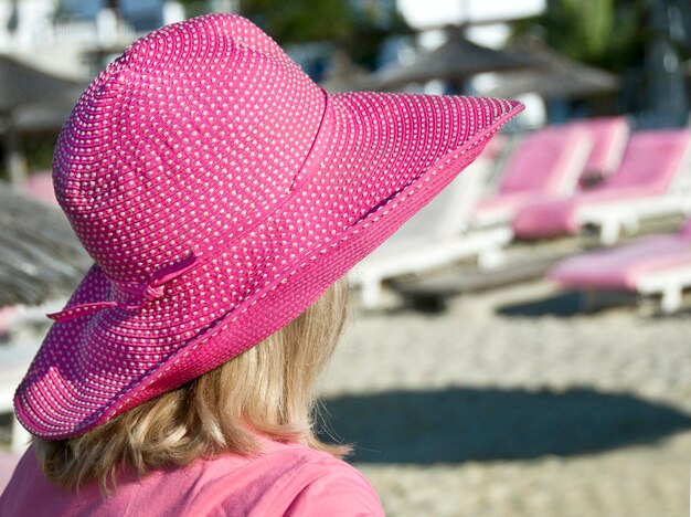 Close-up de mulher vestindo chapéu rosa na praia