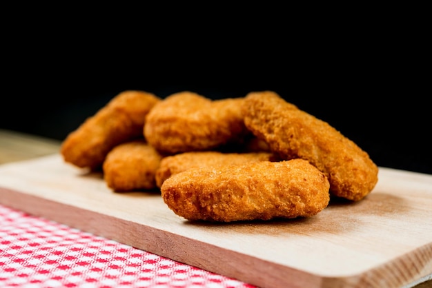 Close-up de nuggets de frango na mesa contra fundo preto