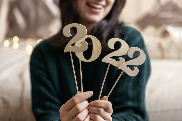 Foto close-up de números de madeira 2022 em varas nas mãos de uma menina, sobre um fundo desfocado.