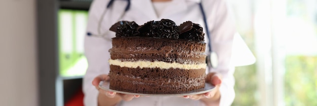 Close-up de nutricionista mulher segurando um grande bolo de chocolate nas mãos Nutricionista adverte contra comer demais e comer conceito de junk food