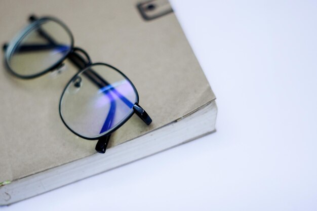 Foto close-up de óculos com livro sobre fundo branco