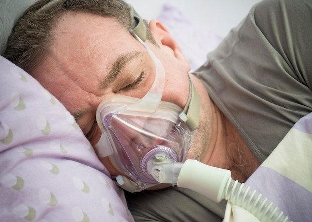 Foto close-up de paciente usando máscara de oxigênio enquanto deitado na cama no hospital