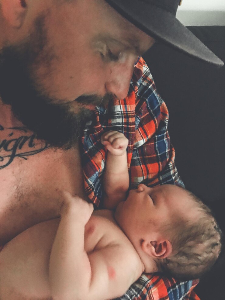 Foto close-up de pai carregando filho sem camisa em casa
