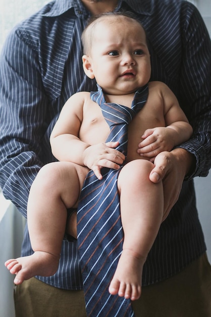 Close-up de pai irreconhecível segurando seu bebê bonito usando uma gravata em braços foto de recém-nascido engraçado c