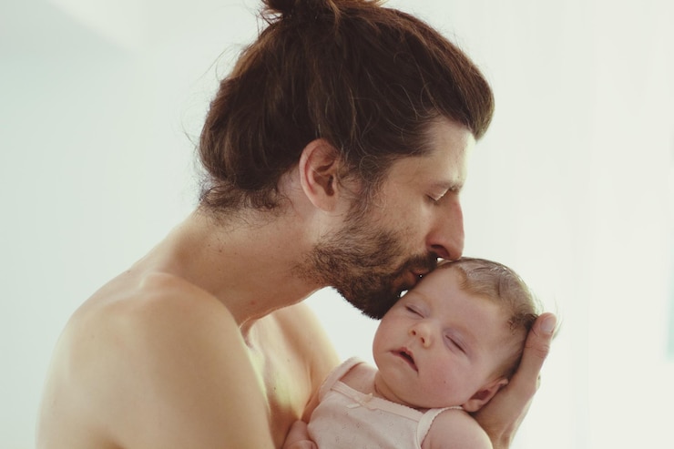 Foto close-up de pai sem camisa beijando filha bebê contra fundo branco