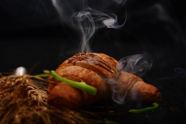 Foto close-up de pão de comida castanho com fumaça contra fundo preto