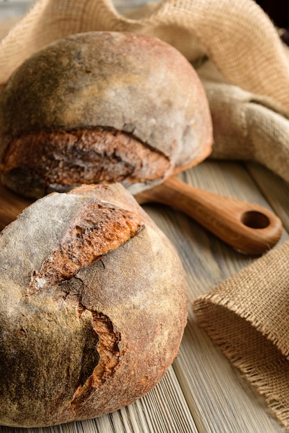 Close-up de pão escuro com estopa e tábua de cortar.