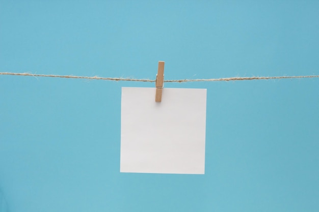 Foto close-up de papel pendurado na corda de roupa em fundo azul