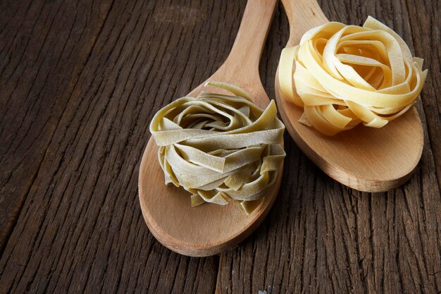 Foto close-up de pasta tagliatelle em colheres de madeira na mesa