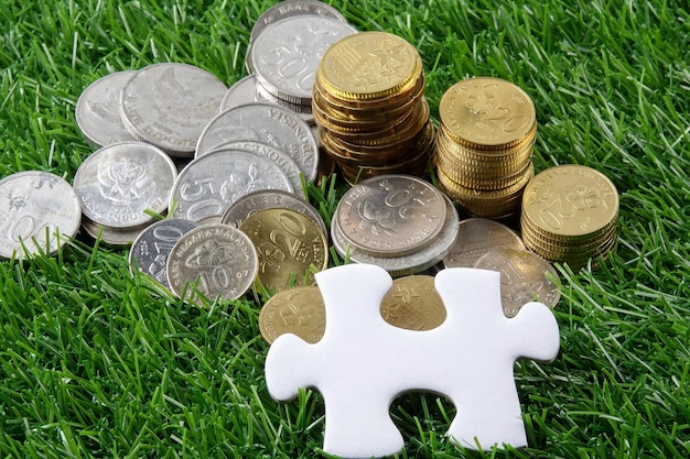Foto close-up de peça de quebra-cabeça com moedas em campo gramado