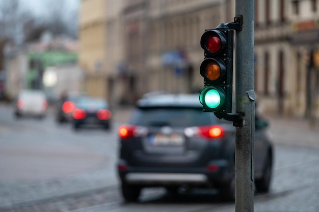close-up de pequeno semáforo de trânsito com luz verde no contexto do trânsito da cidade