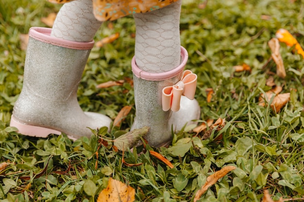 Close-up de pés de bebê em botas de borracha. a criança corre através das poças em um dia de outono.