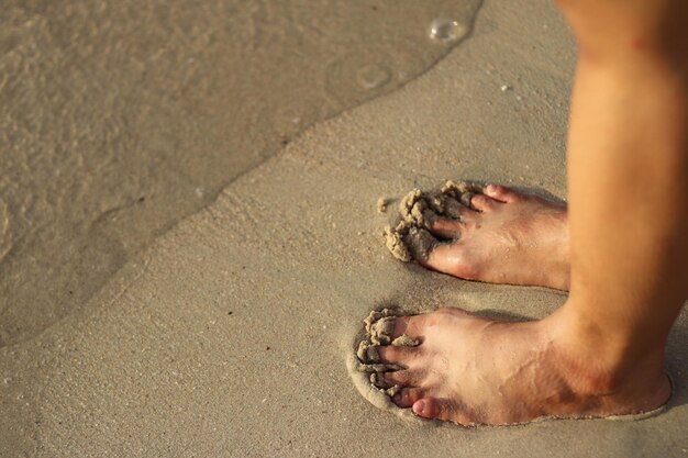 close-up de pés em pé na praia de areia