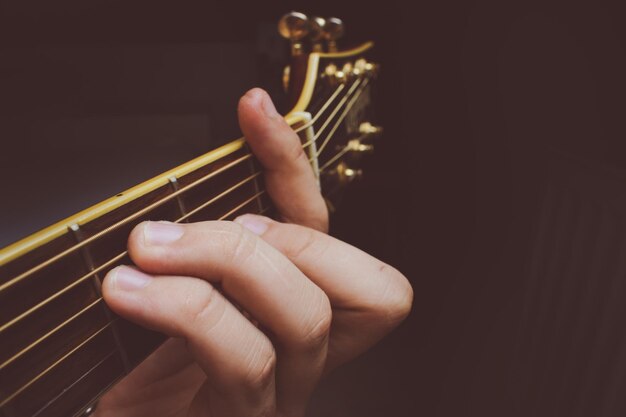 Foto close-up de pessoa tocando guitarra contra fundo preto