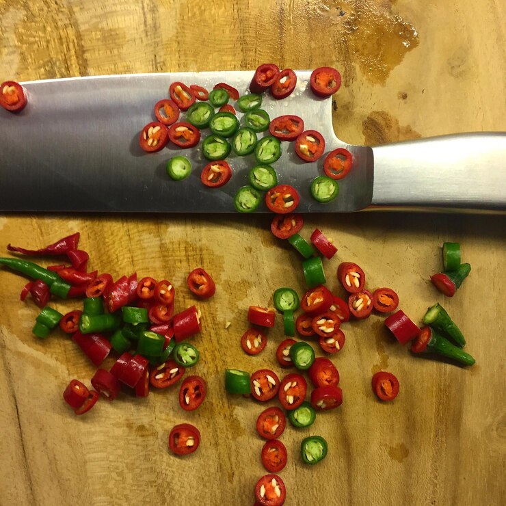 Foto close-up de pimentas picadas com uma faca na tábua de cortar