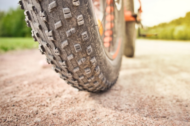 Close-up de pneu gordo de mountain bike na estrada suja. roda de bicicleta gorda. conceito de atividade ao ar livre de verão.